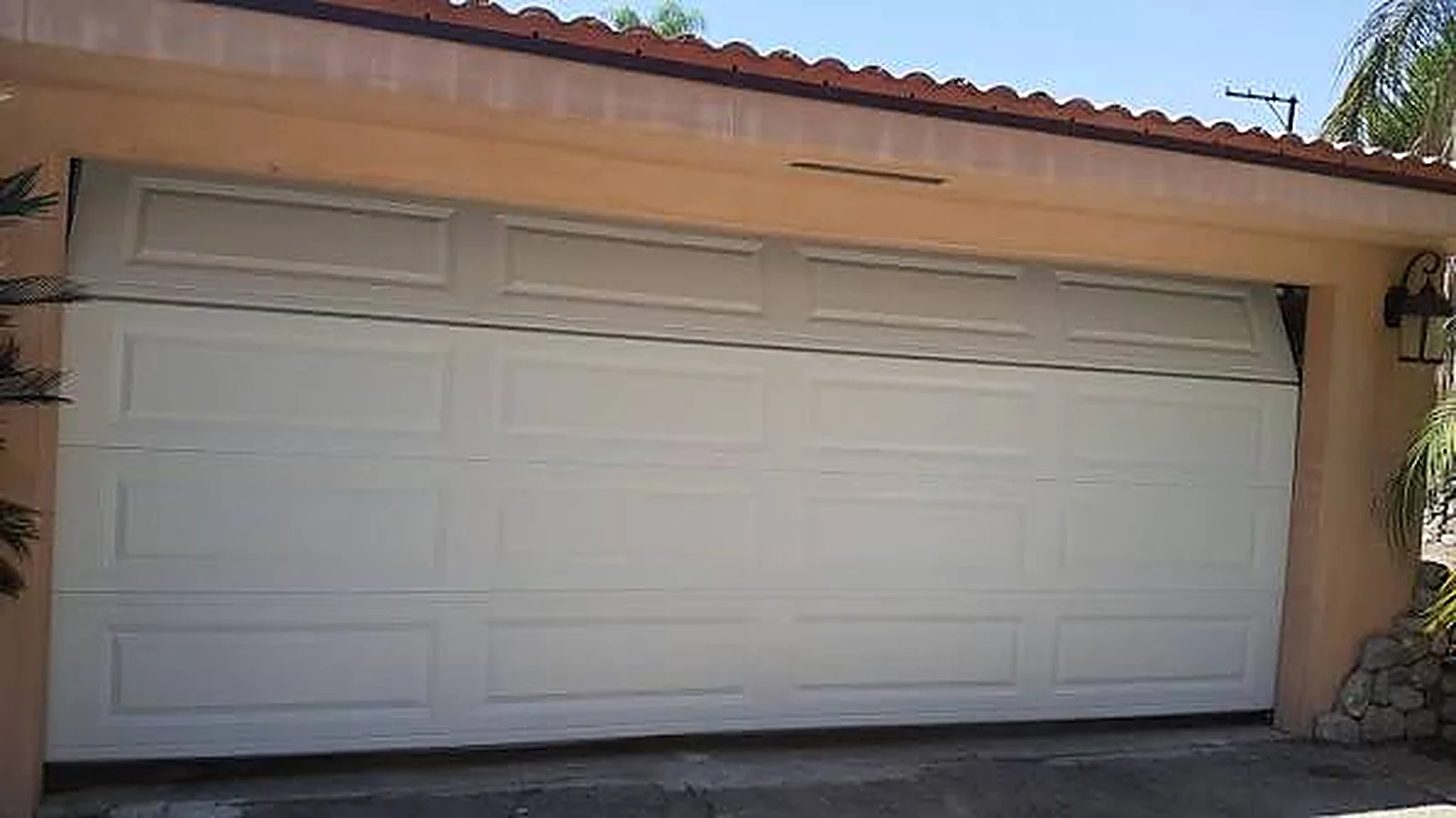 Cream double garage door with a moulded wood-grain finish