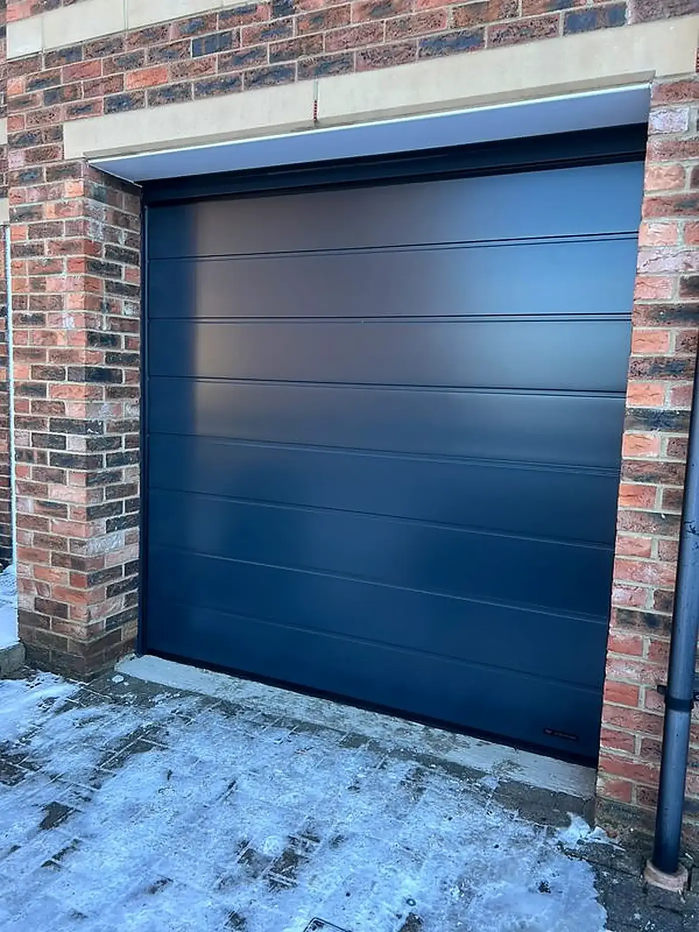 Navy steel sectional garage door on a brick home