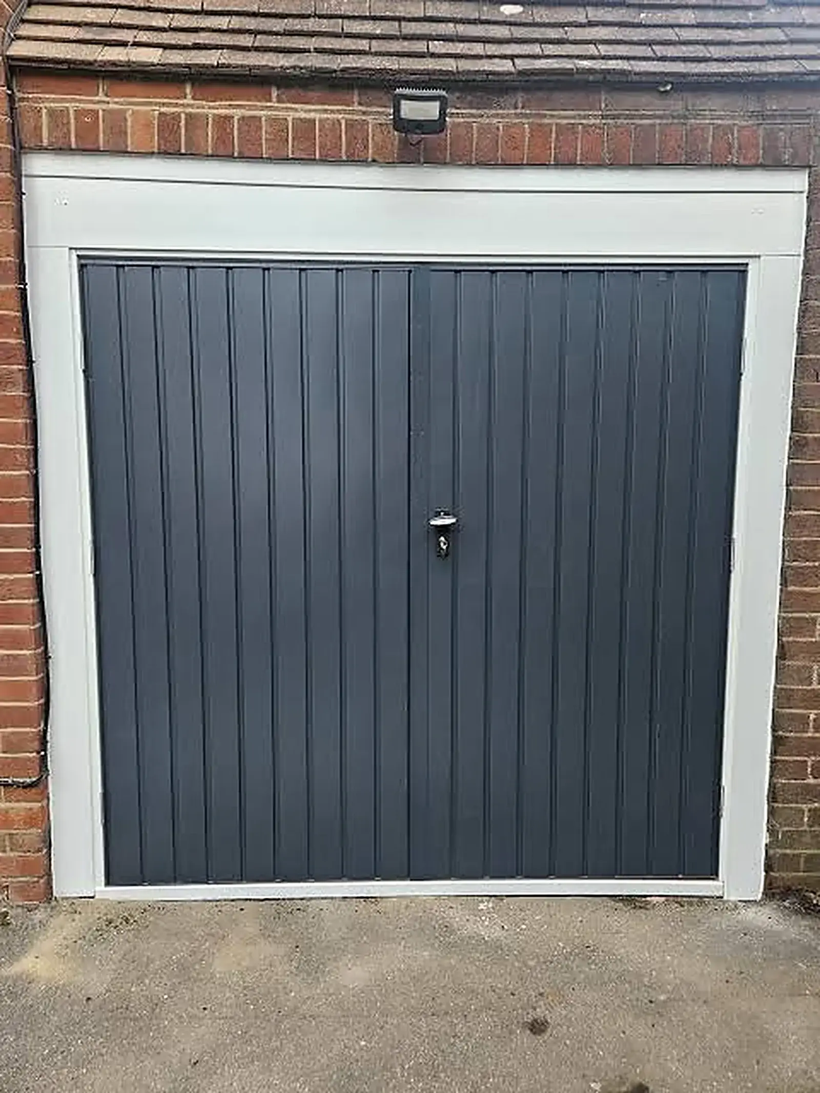 Grey single tip-up garage door on an older suburban home